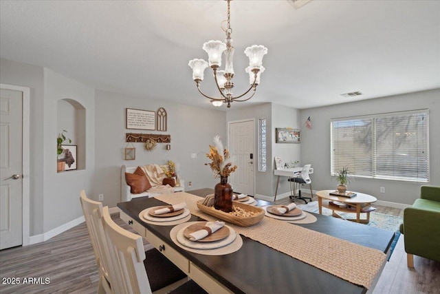 dining space with wood-type flooring and a notable chandelier