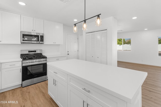 kitchen featuring light hardwood / wood-style floors, white cabinets, a kitchen island, stainless steel appliances, and decorative light fixtures