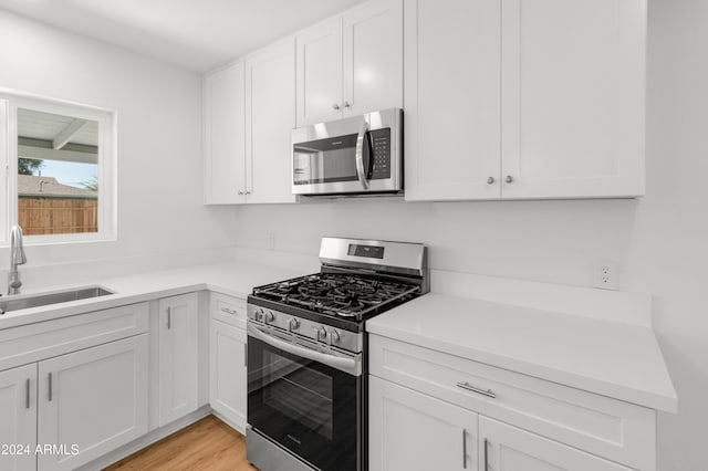 kitchen featuring light hardwood / wood-style floors, stainless steel appliances, sink, and white cabinetry