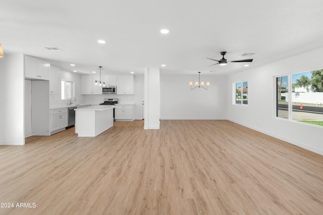 unfurnished living room with sink, ceiling fan with notable chandelier, and light hardwood / wood-style floors