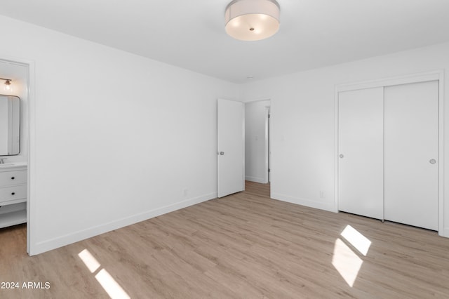 unfurnished bedroom with light hardwood / wood-style floors, ensuite bathroom, and a closet