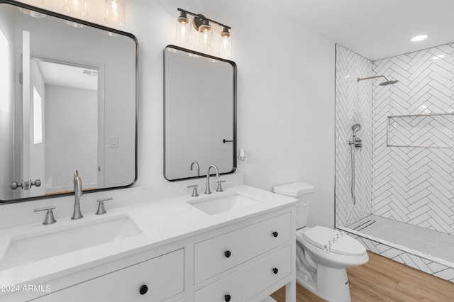 bathroom with hardwood / wood-style floors, tiled shower, vanity, and toilet