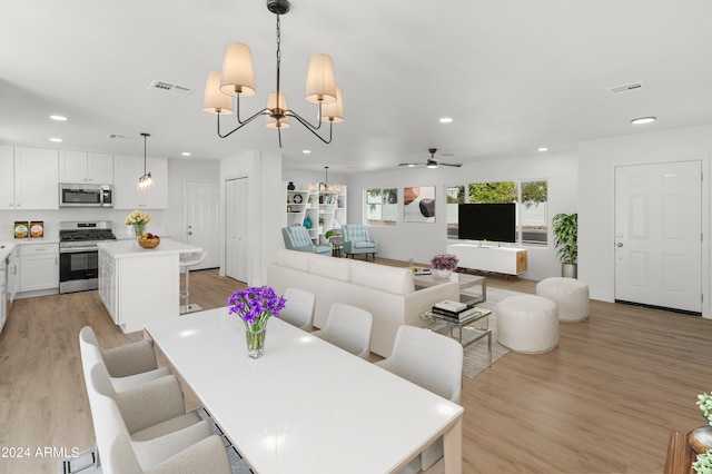 dining space featuring ceiling fan with notable chandelier and light wood-type flooring