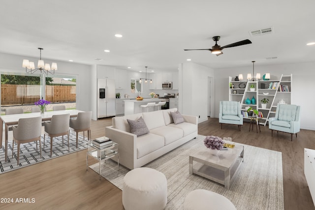 living room featuring light wood-type flooring and ceiling fan with notable chandelier