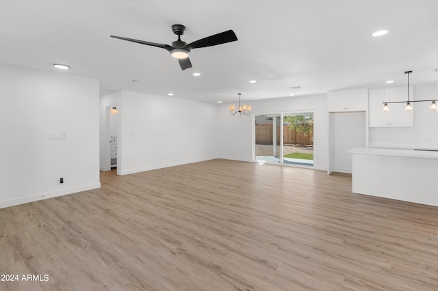 unfurnished living room with ceiling fan with notable chandelier and light wood-type flooring