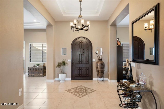 foyer entrance featuring a chandelier, light tile patterned floors, and a raised ceiling