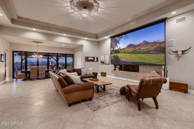 home theater room with a tray ceiling, light tile patterned floors, and a notable chandelier