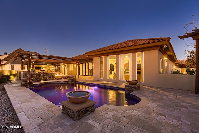 pool at dusk featuring an outdoor kitchen and a patio