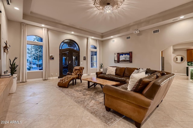 tiled living room featuring a high ceiling and a raised ceiling