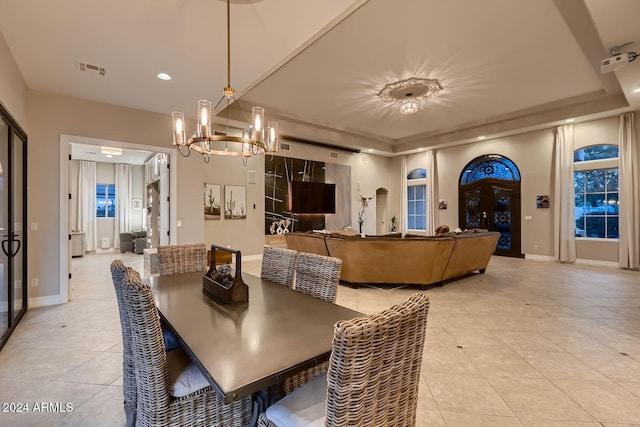 tiled dining room featuring a tray ceiling and an inviting chandelier