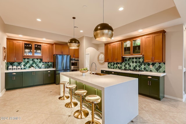 kitchen with a kitchen island with sink, decorative backsplash, sink, and hanging light fixtures