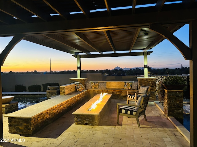 patio terrace at dusk featuring a fire pit and a pergola