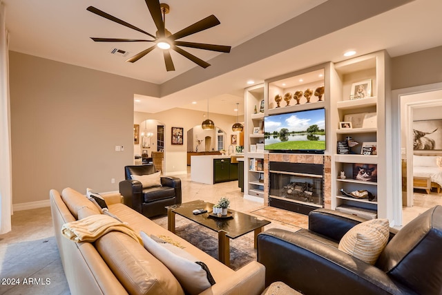 tiled living room with a tile fireplace, ceiling fan, and built in features