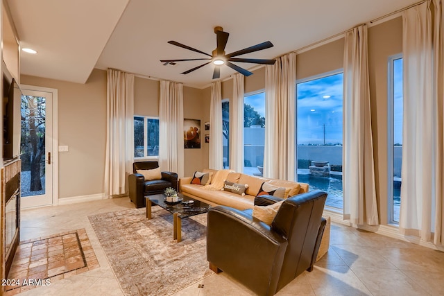 tiled living room with a water view and ceiling fan