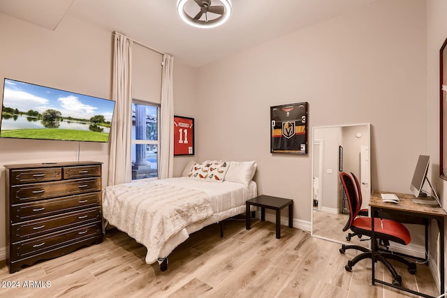 bedroom featuring light wood-type flooring and a towering ceiling