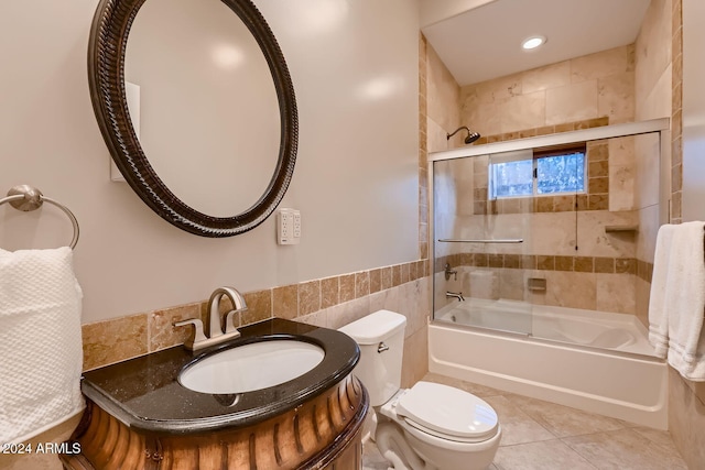 full bathroom featuring combined bath / shower with glass door, vanity, tile walls, tile patterned flooring, and toilet