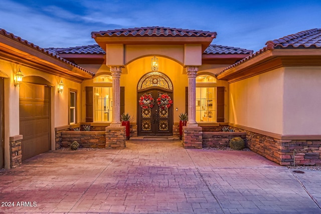 exterior entry at dusk featuring french doors and a garage