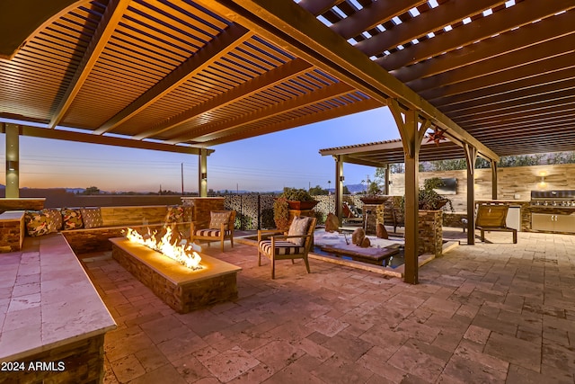 patio terrace at dusk featuring a pergola, area for grilling, and an outdoor fire pit