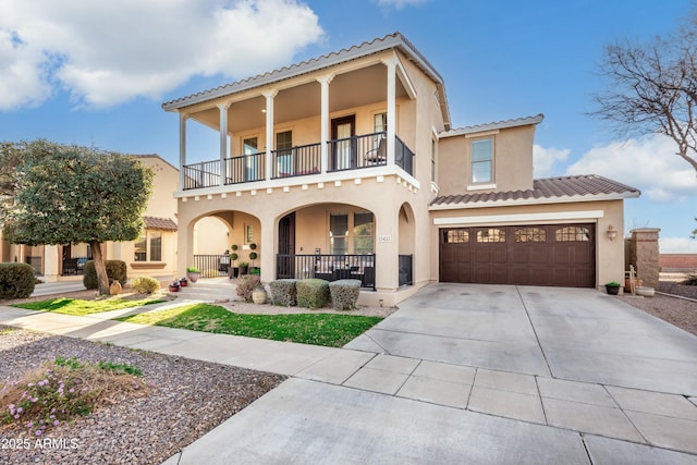 mediterranean / spanish house featuring a balcony, a garage, and covered porch