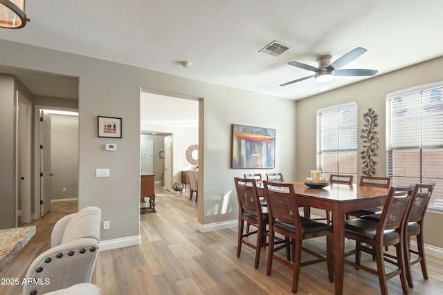 dining area with ceiling fan, a textured ceiling, and light hardwood / wood-style floors