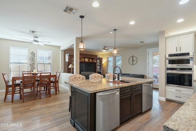 kitchen with light stone counters, sink, stainless steel appliances, and white cabinets