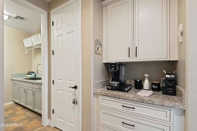 bar featuring sink and light stone counters