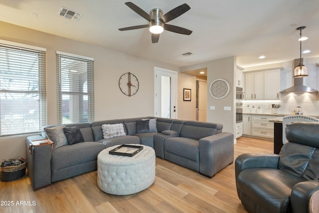 living room featuring ceiling fan and light hardwood / wood-style flooring