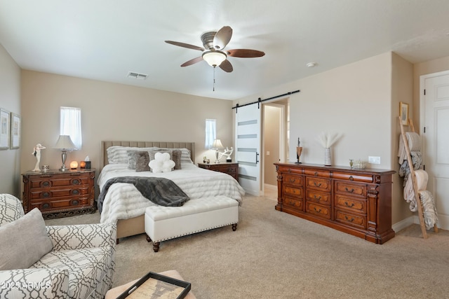 carpeted bedroom featuring multiple windows, a barn door, and ceiling fan