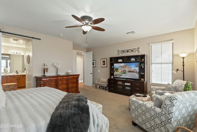 carpeted bedroom with ceiling fan, connected bathroom, a barn door, and sink