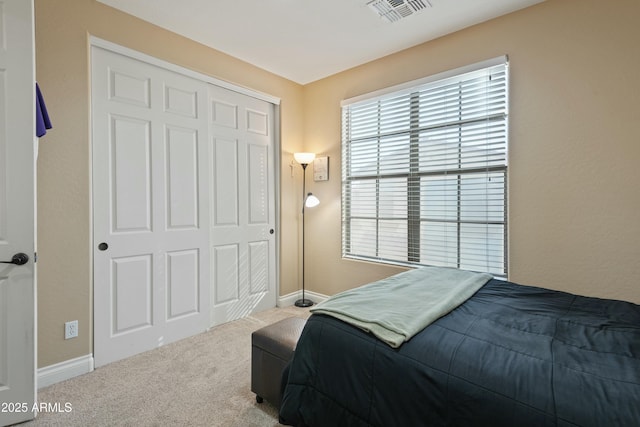 carpeted bedroom featuring multiple windows and a closet