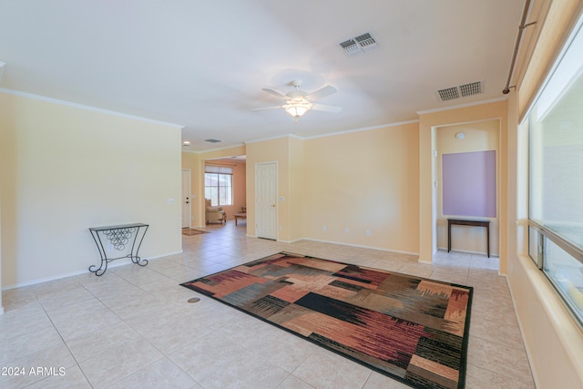 tiled empty room with ornamental molding, visible vents, baseboards, and a ceiling fan