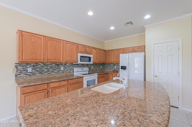 kitchen featuring a center island with sink, visible vents, decorative backsplash, a sink, and white appliances