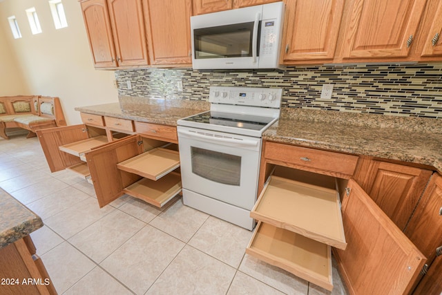 kitchen featuring light tile patterned floors, white appliances, stone counters, and tasteful backsplash