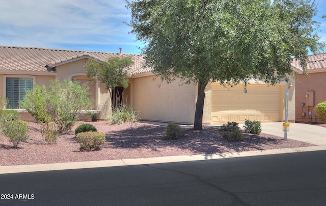 view of front of property featuring stucco siding, a garage, driveway, and a tile roof