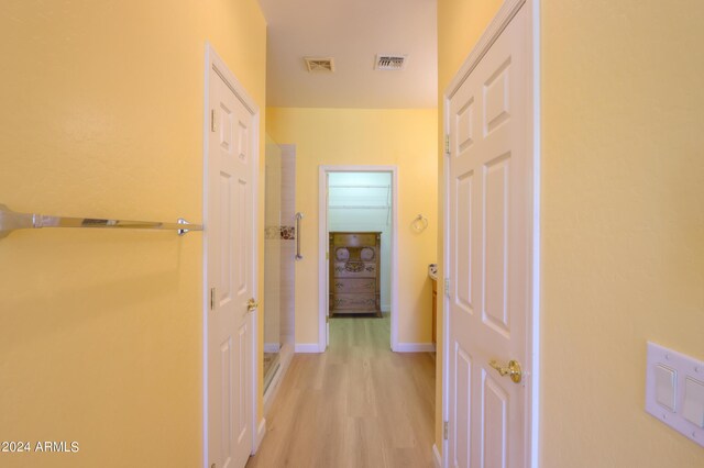 corridor featuring light wood-style flooring, visible vents, and baseboards