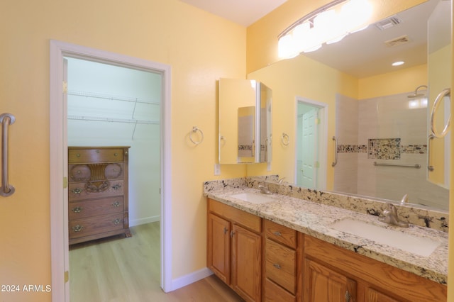 bathroom featuring visible vents, wood finished floors, a walk in closet, and a sink