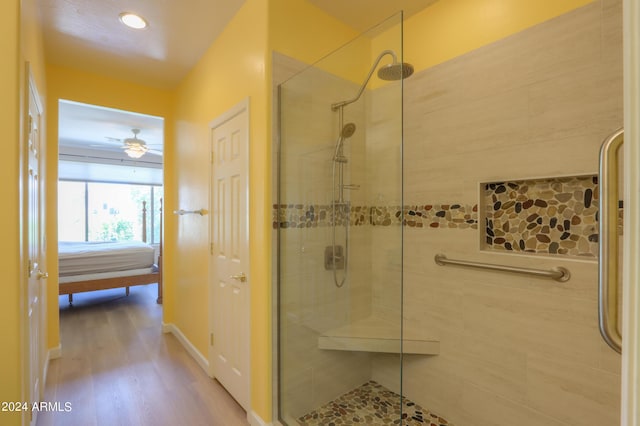 full bath with a tile shower, baseboards, and wood finished floors