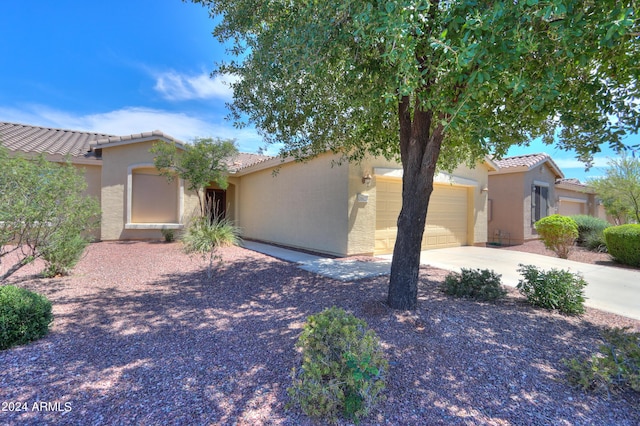 view of front of house with a tile roof, driveway, an attached garage, and stucco siding