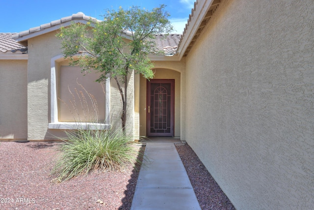 entrance to property with a tile roof and stucco siding