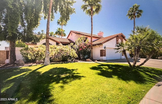 mediterranean / spanish-style house featuring an attached garage, a tile roof, a front yard, a chimney, and driveway