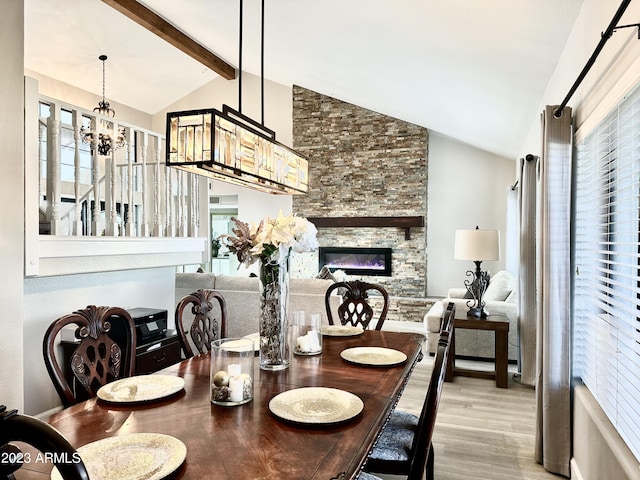 dining room with a wealth of natural light, a fireplace, lofted ceiling with beams, and wood finished floors