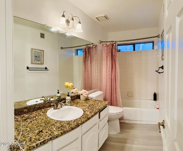 full bath with visible vents, shower / bath combo with shower curtain, toilet, wood finished floors, and vanity