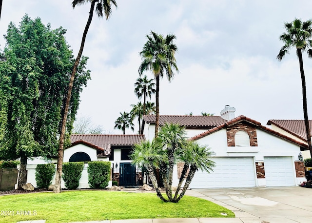 mediterranean / spanish house featuring a fenced front yard, a tiled roof, concrete driveway, and a garage