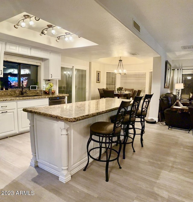 kitchen featuring light stone counters, a notable chandelier, white cabinetry, and a sink