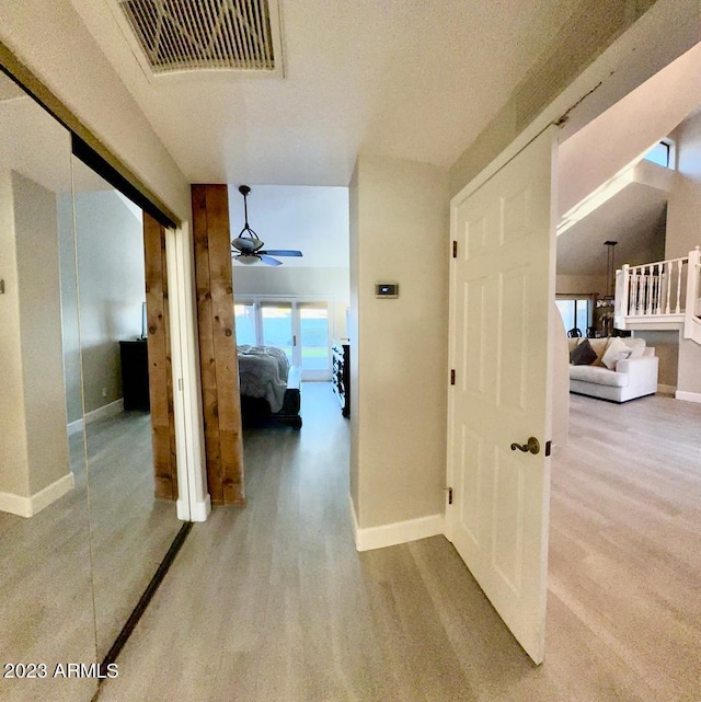 hall featuring visible vents, baseboards, and wood finished floors