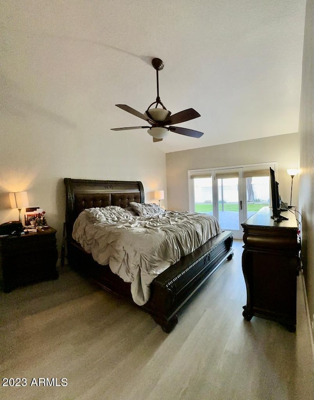 bedroom featuring wood finished floors, lofted ceiling, access to exterior, and a ceiling fan