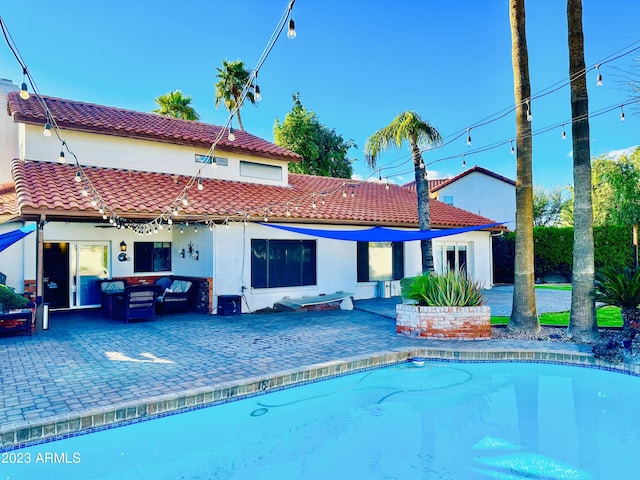 back of house featuring a tiled roof, stucco siding, an outdoor pool, and a patio