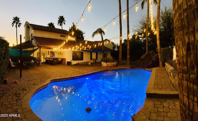 pool at dusk featuring a patio area and an outdoor pool