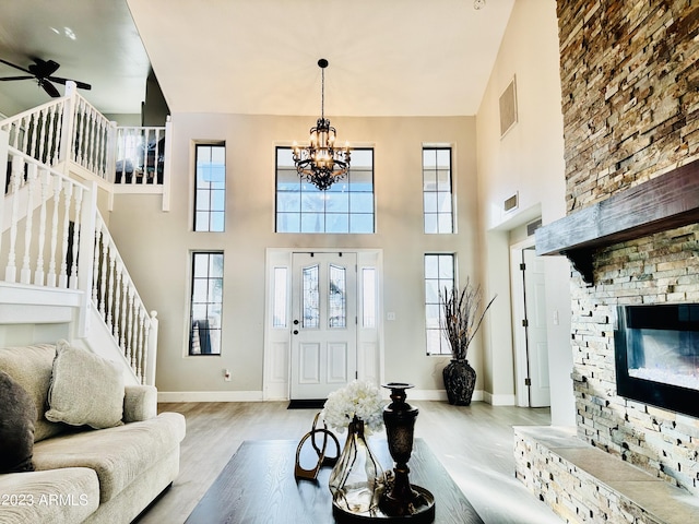 foyer featuring stairway, ceiling fan with notable chandelier, visible vents, and wood finished floors