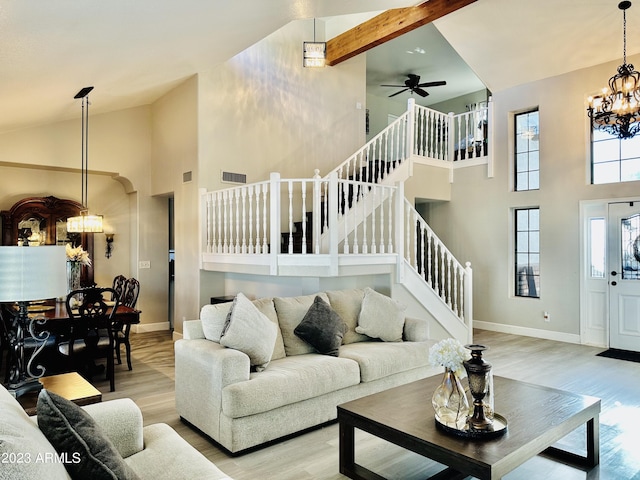 living area featuring stairs, light wood-style floors, baseboards, and high vaulted ceiling